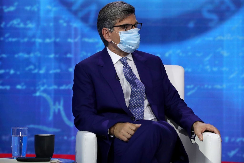 Stephanopoulos, wearing a blue suit and a medical mask, is seated onstage at a televised event against a blue backdrop.