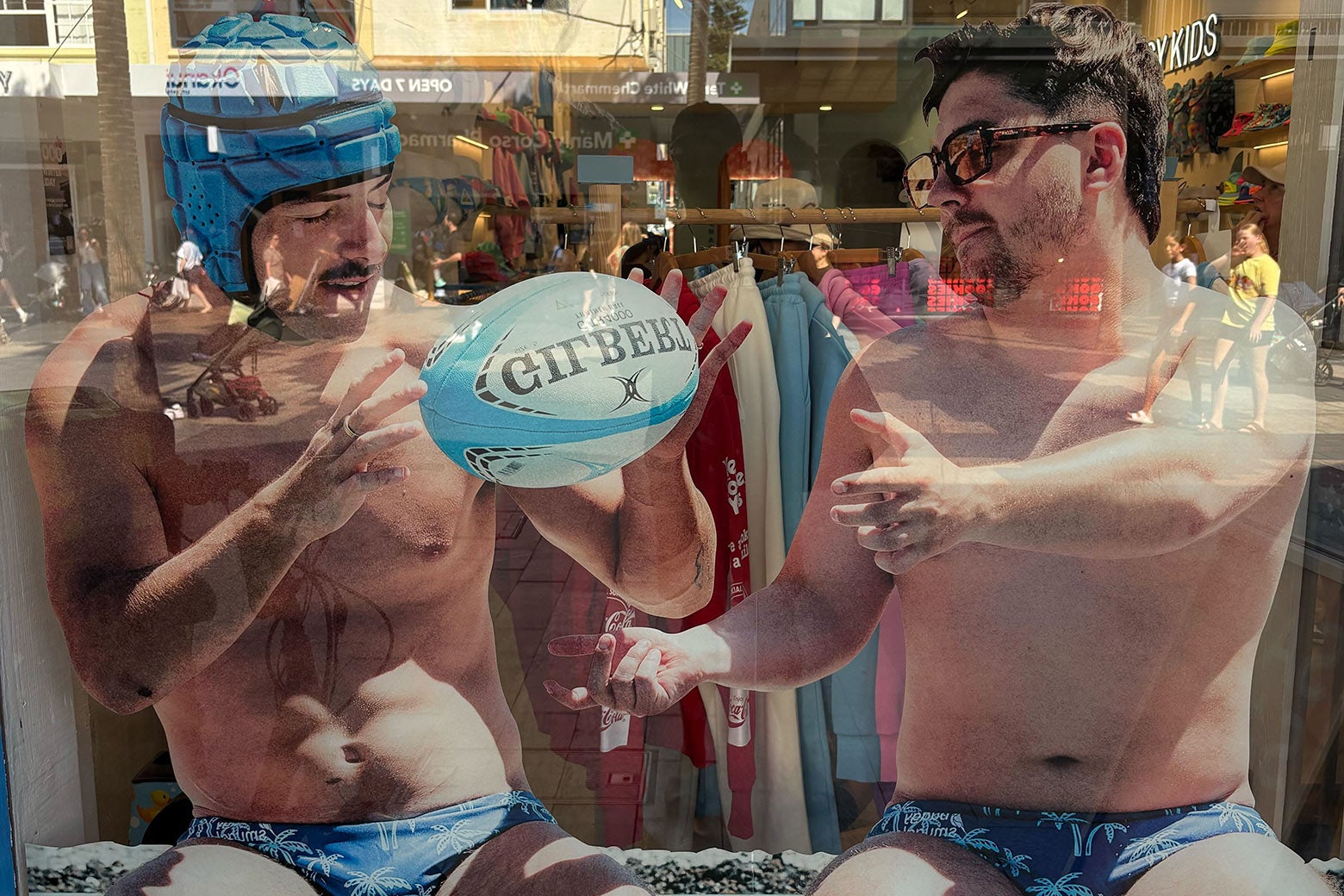 Two men playing with a water rugby ball and wearing Speedos.