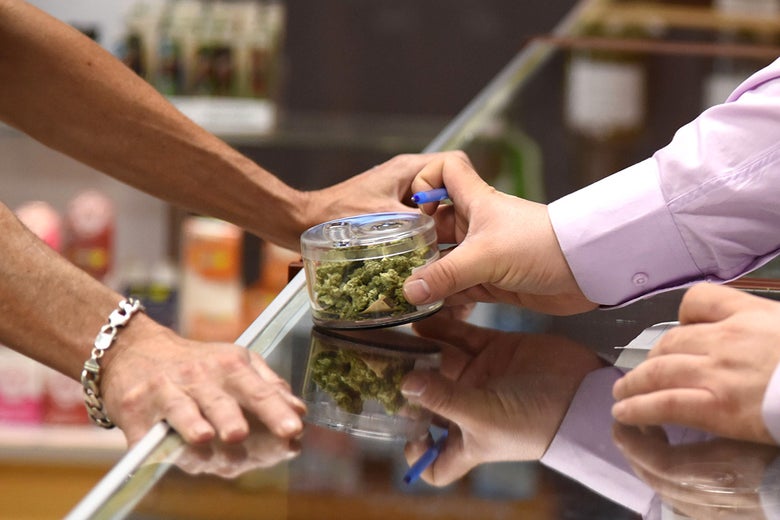A budtender shows cannabis buds to a customer at the Green Pearl Organics dispensary in Desert Hot Springs, California, on Monday, the first day of legal recreational marijuana sales in the state.