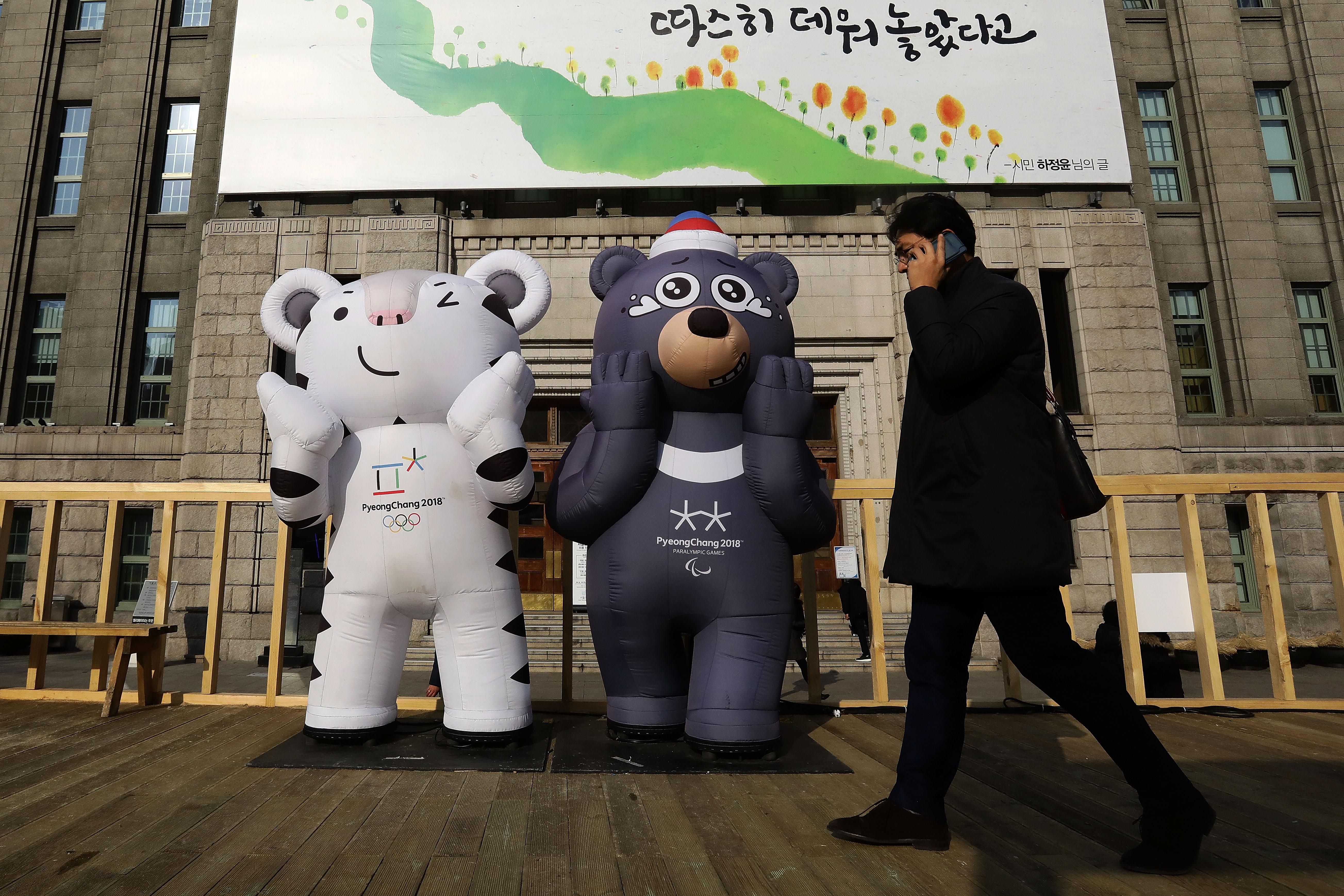A South Korean man walks past the mascots of the 2018 PyeongChang Winter Olympic and Paralympic Games Soohorang (L) and Bandabi (R) on January 5, 2018 in Seoul, South Korea. North Korea accepted a proposal to hold talks with South Korea on Jan. 9 ahead of the Winter Olympics in February.  