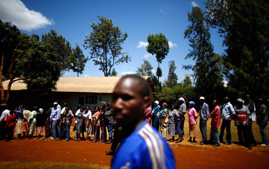 People wait in line to cast their ballots in front of a polling station in Kenya's town of Gatundu March 4, 2013. 