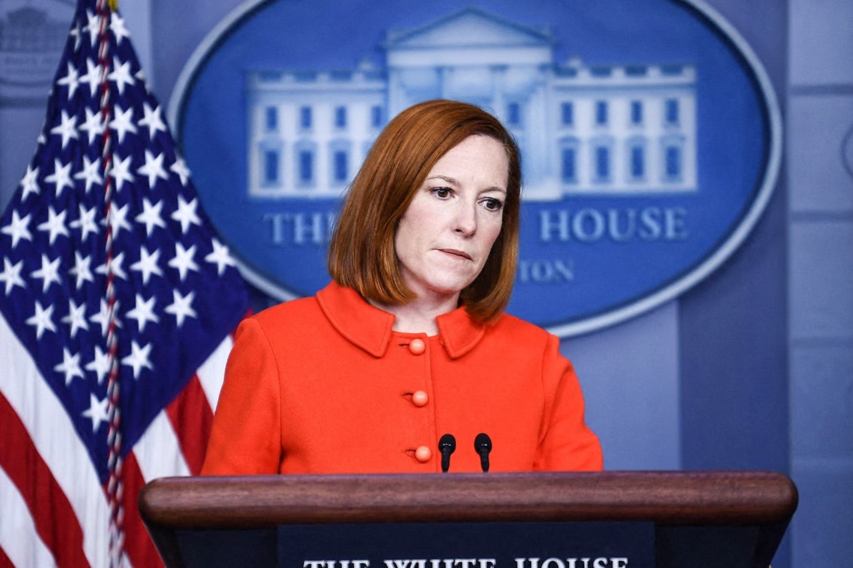 Jen Psaki purses her lips as she stands at a podium in the briefing room