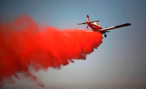 A tanker airplane drops fire retardant on a wildfire.