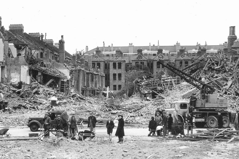 People stand amid rubble and bombed-out buildings.