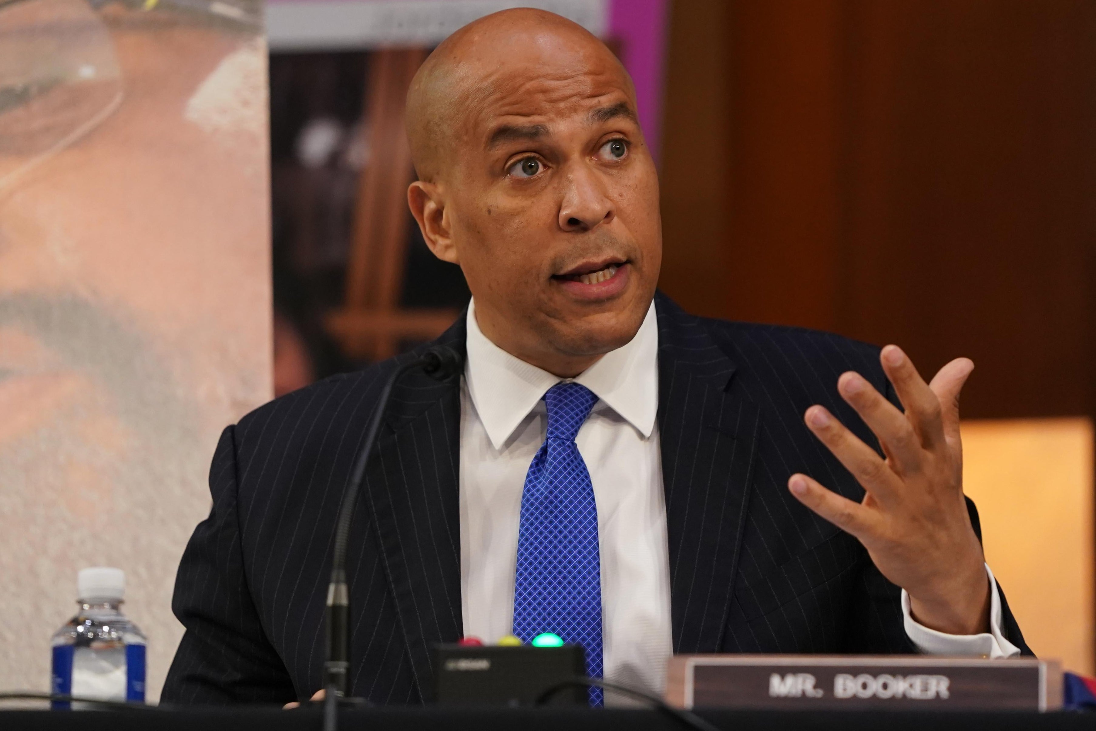 Cory Booker gestures while seated in a hearing room.
