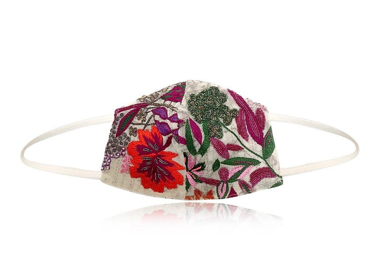 A face mask with hand-embroidered multicolor flowers and leaves on a white background