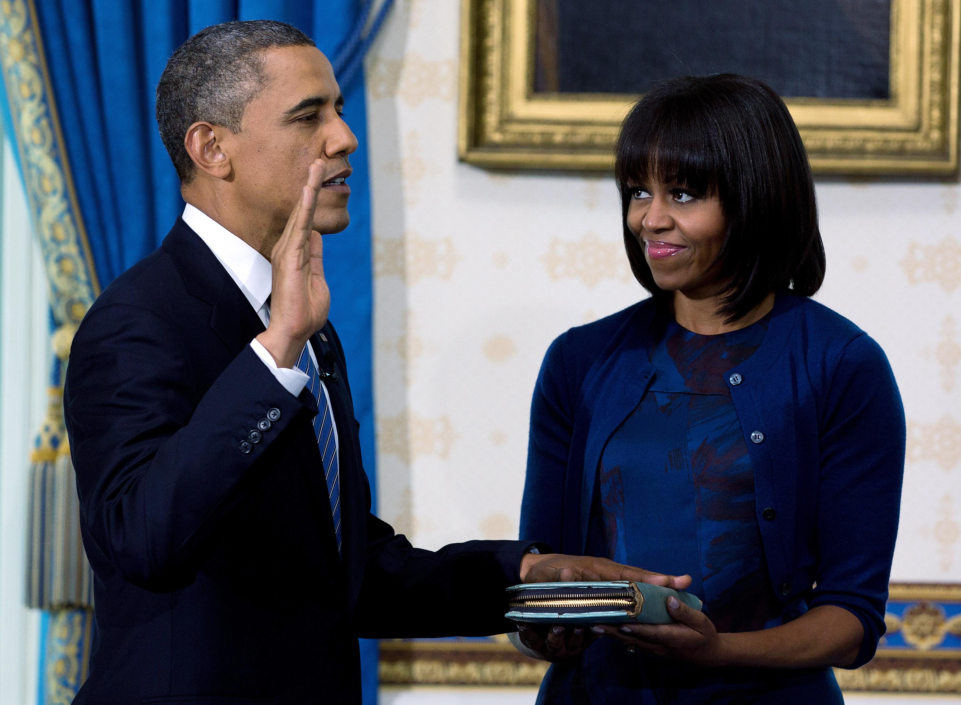 Barack Obama takes the oath of office as first lady Michelle Obama holds the Bible.
