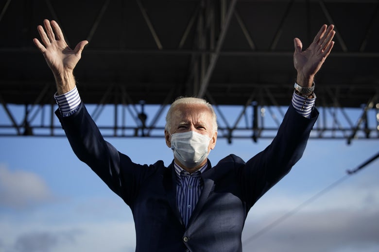 Joe Biden wearing a mask and raising his arms