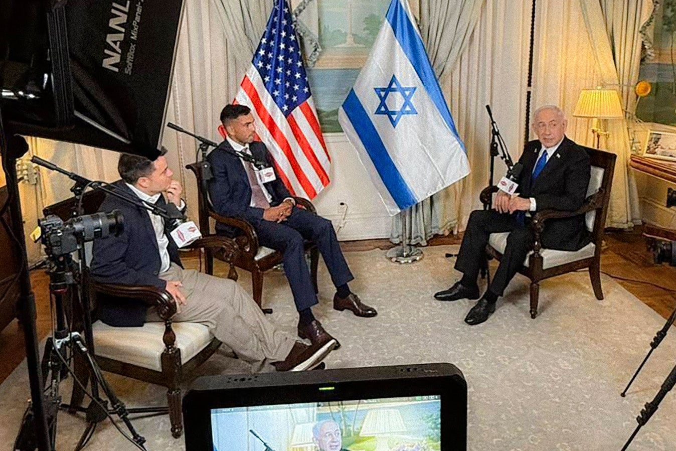 Israeli Prime Minister Benjamin Netanyahu sits for an interview with the Nelk Boys with a U.S. and an Israeli flag in the background.