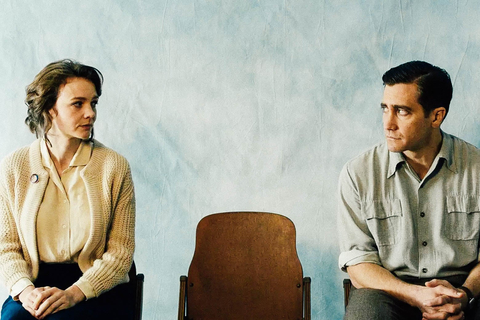Carey Mulligan and Jake Gyllenhaal stare at each other while seated on either side of an empty chair.