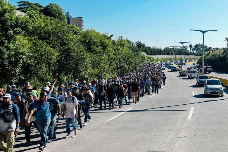 A group of migrants takes up one lane of a highway.