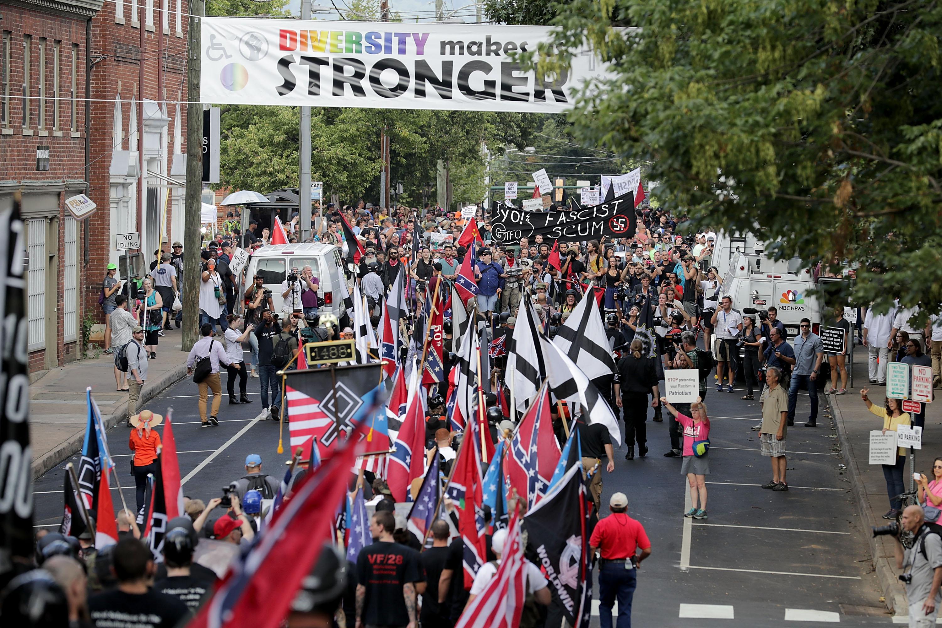 White nationalists and neo-Nazis holding flags march down a street in Charlottesville.