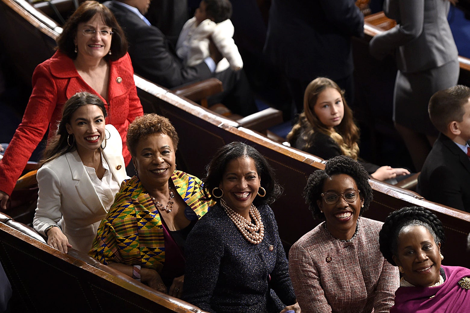 Second from left: Reps. Alexandria Ocasio-Cortez, Barbara Lee, Jahana Hayes, Lauren Underwood, and Sheila Jackson-Lee sit for a photograph on the House Chamber during the opening session of the 116th Congress on Jan. 3. A sixth women, smiling and standing to the left of Ocasio-Cortez, is unidentified in the photo.