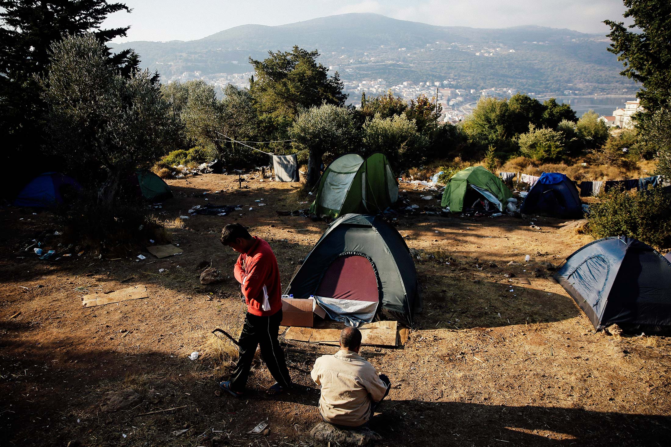 Migrants stand next to tents at a makeshift camp on the Greek island of Samos. 