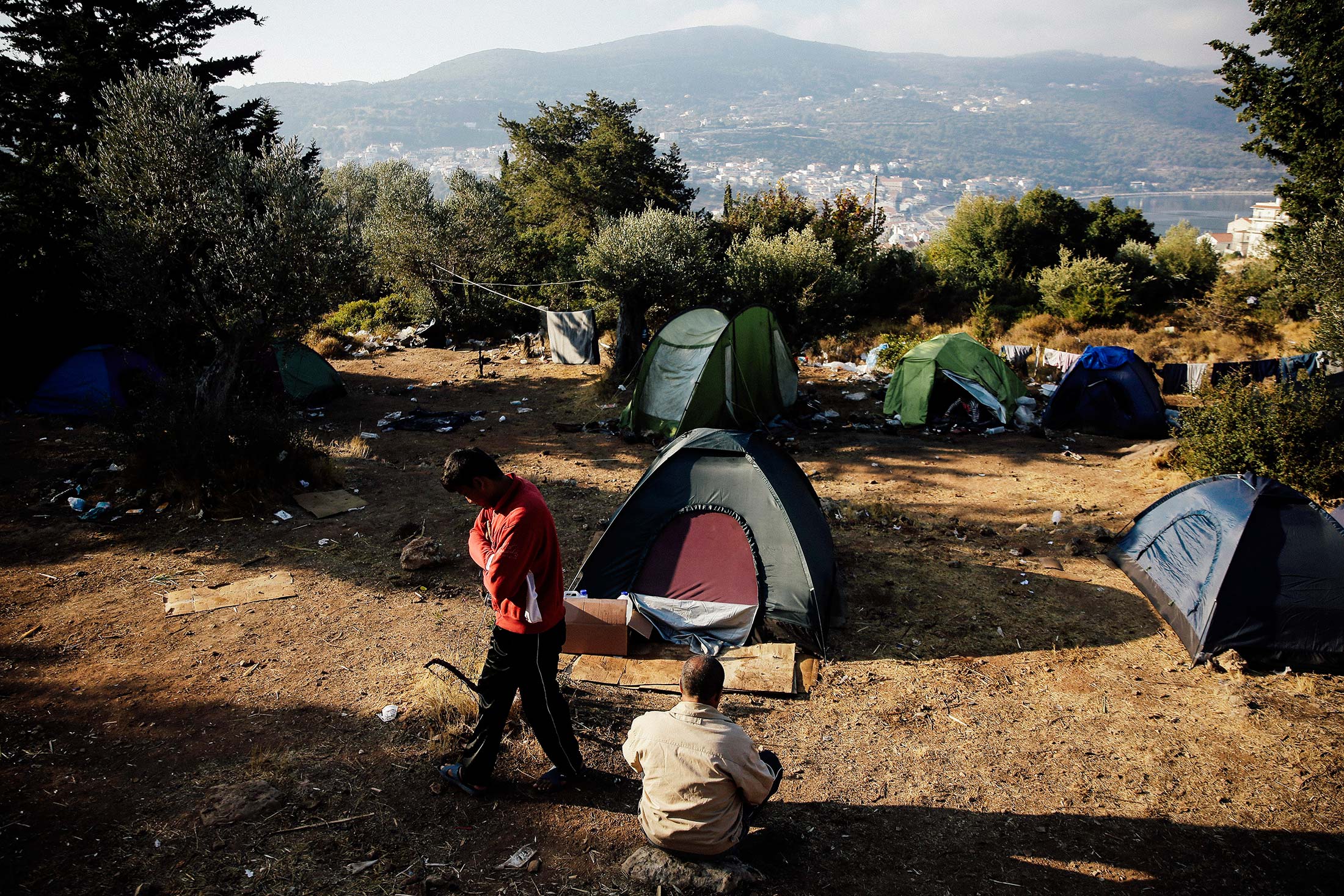 Migrants stand next to tents at a makeshift camp on the Greek island of Samos.