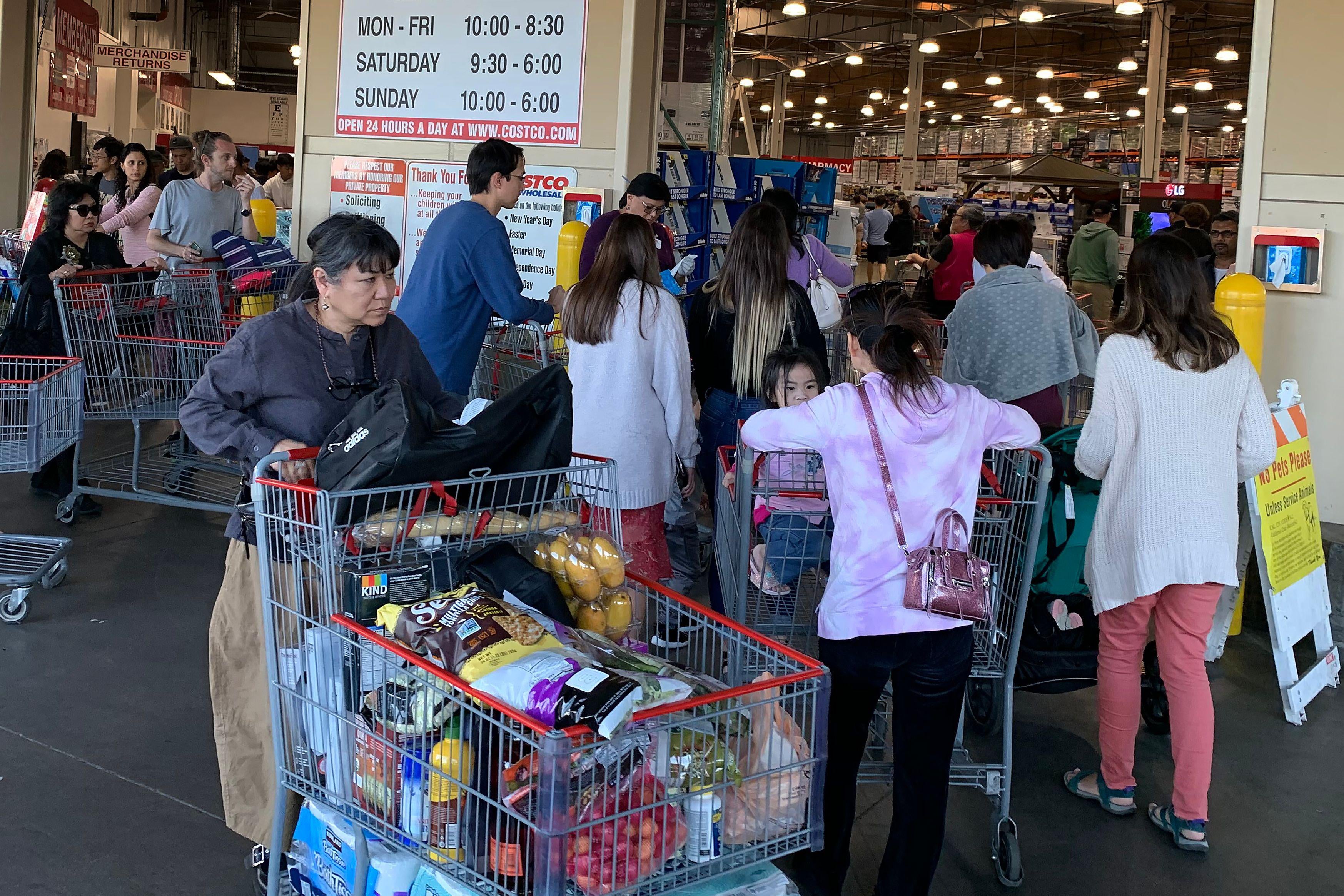 Crowd of shoppers at Costco, with carts filled with household essentials