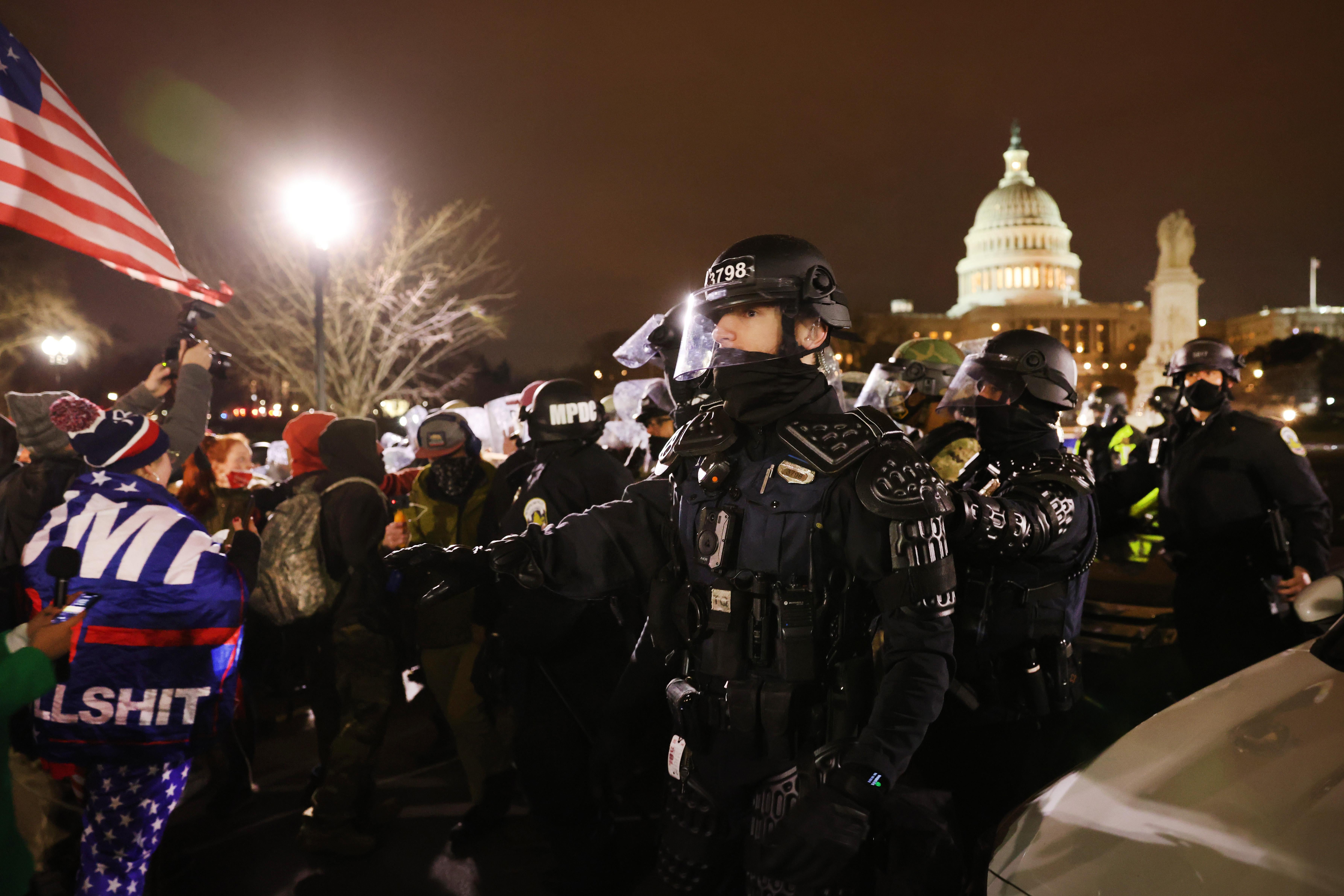 National Guard members and D.C. police in riot gear corral a large crowd of Trump supporters in front of the Capitol at night after the attack on January 6