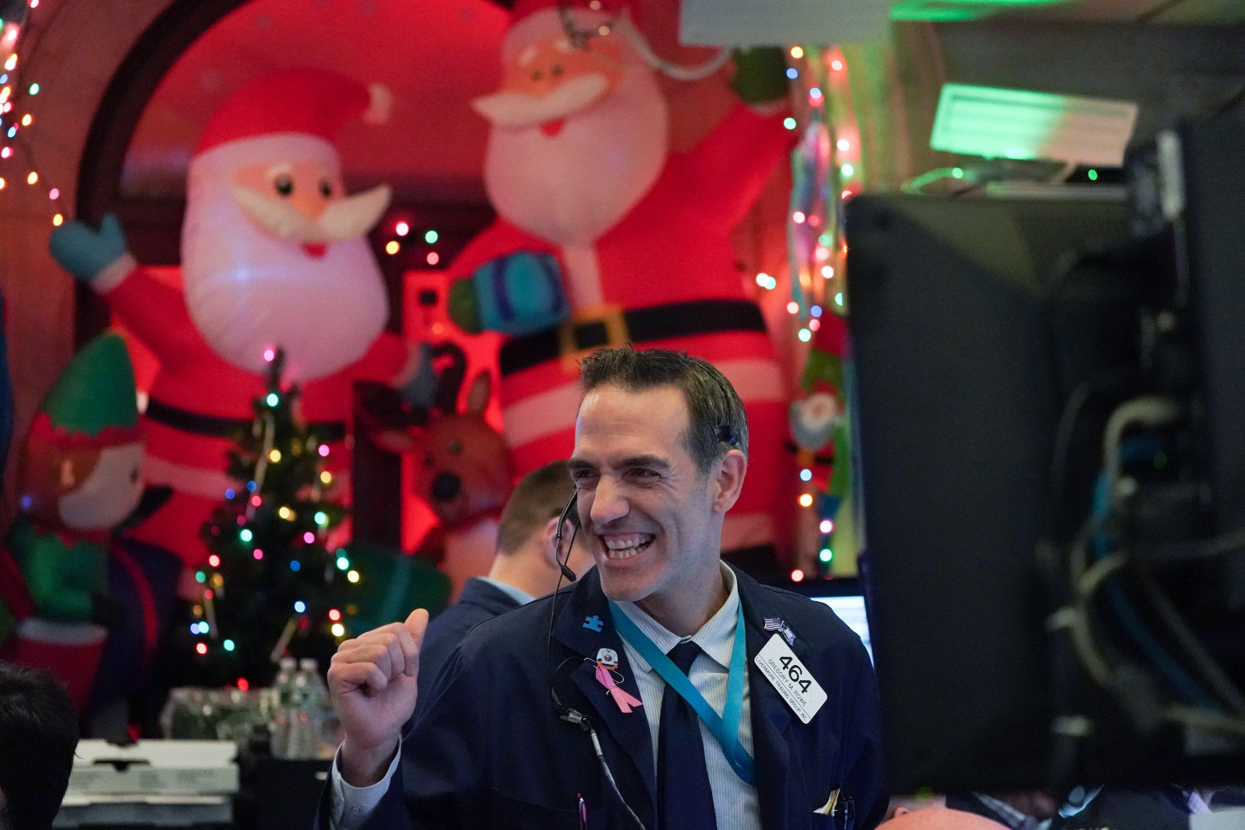 A trader pumps his fist at the closing bell of the New York Stock Exchange on Dec. 5. Inflatable Santas and other Christmas decorations are in the background.