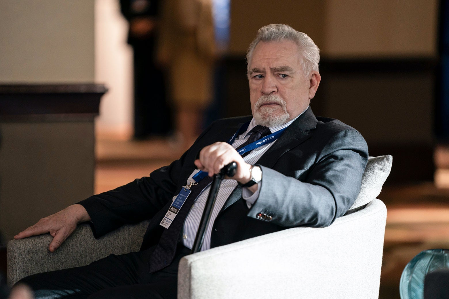 a man with white hair and a white beard in a suit and a chair looking a little annoyed 