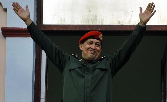 Venezuelan President Hugo Chavez raises his arms.