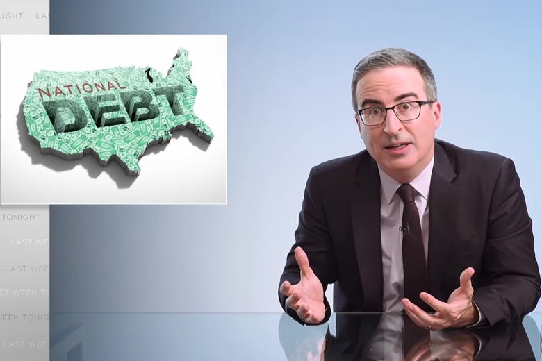 John Oliver sits at an anchorperson's desk in front of a sign reading "National Debt."