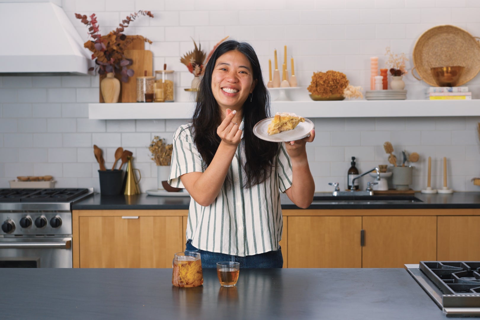 Sue Li in a kitchen holding a slice of apple pie.