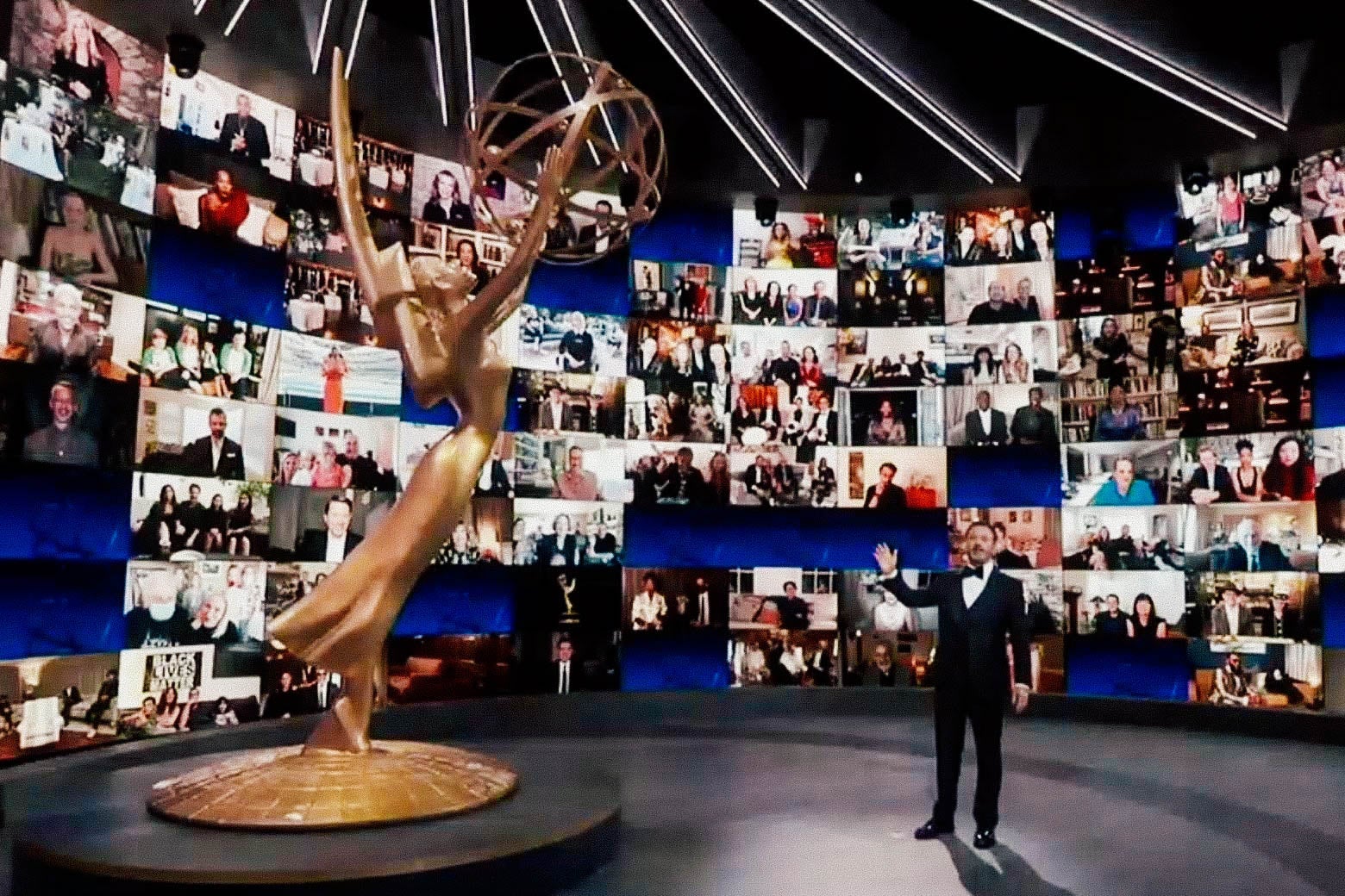 Jimmy Kimmel next to a large Emmys statuette and in front of Zoom screens.