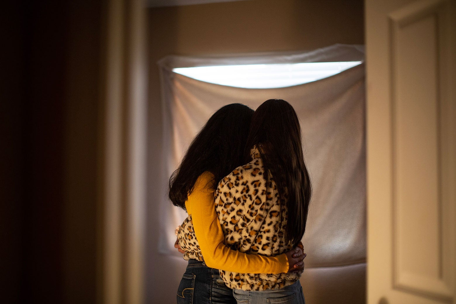 Two girls hug while looking away from the camera.