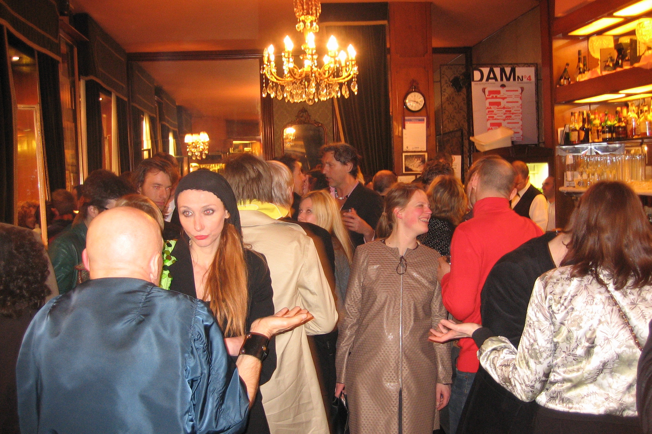 A crowd of dozens of people inside a warmly lit bar.