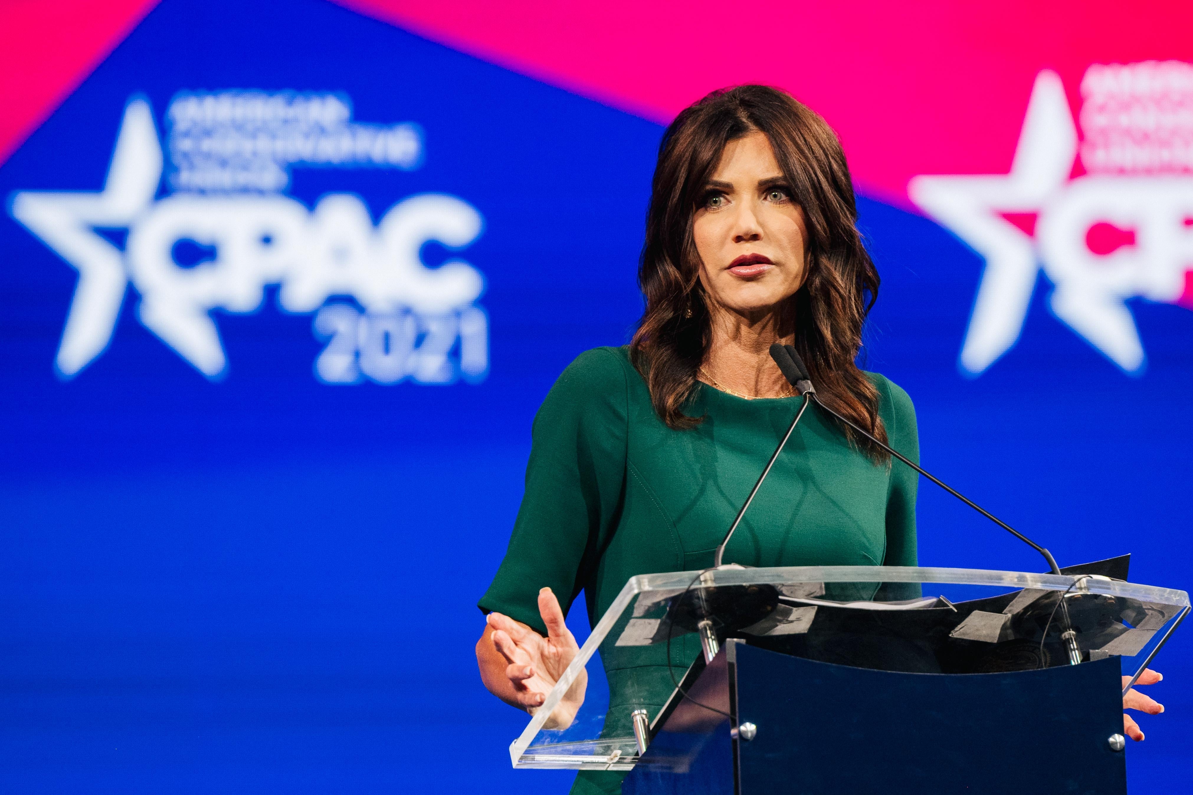 Noem speaks at a podium with the CPAC logo on a backdrop behind her