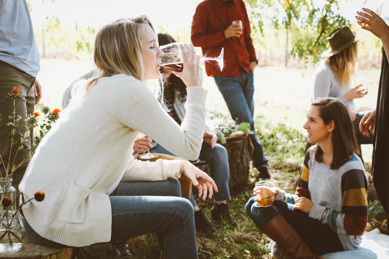 A woman drinking wine at an outdoor party.
