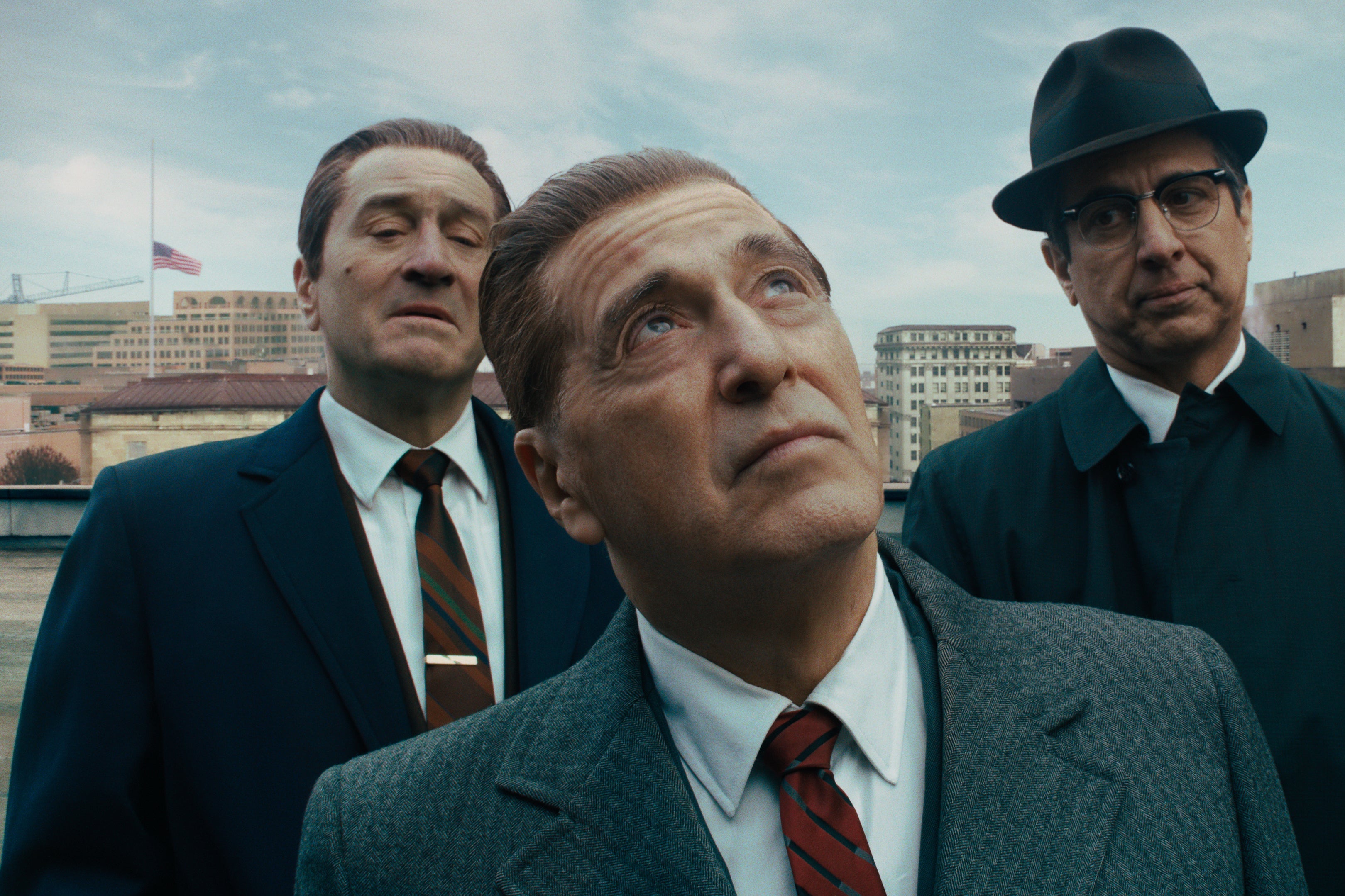 Robert De Niro and Ray Romano stand behind Al Pacino, who looks upward.