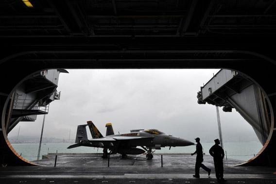 US navy servicemen are seen with an F/A-18 Hornet warplane on the USS George Washington, a nuclear powered aircraft carrier, in Hong Kong on November 9, 2011.