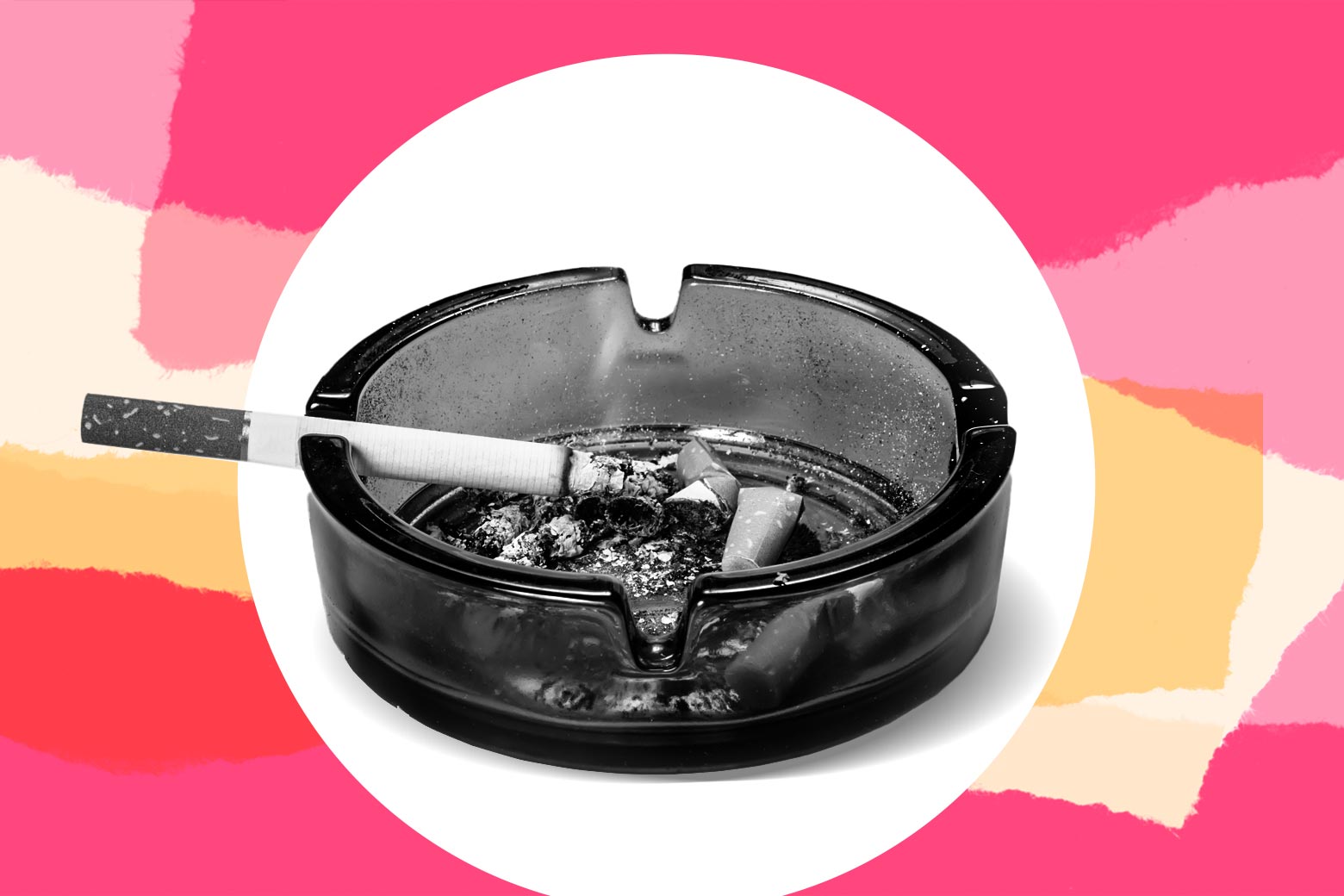 A cigarette laying on an ashtray full of butts