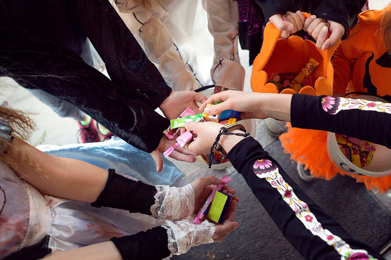 Kids in costumes hold out their hands for candy.