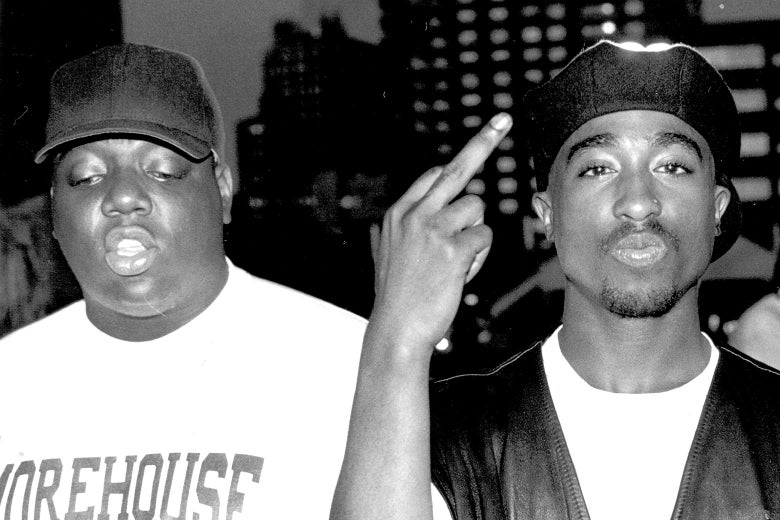 A black-and-white photo of Biggie and Tupac in which Tupac puts up his middle finger.