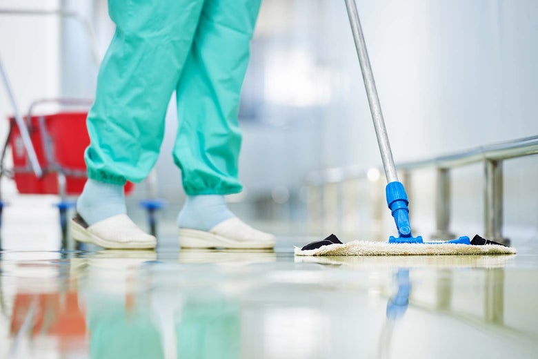 Stock image of a person wearing medical scrubs mopping the floor.