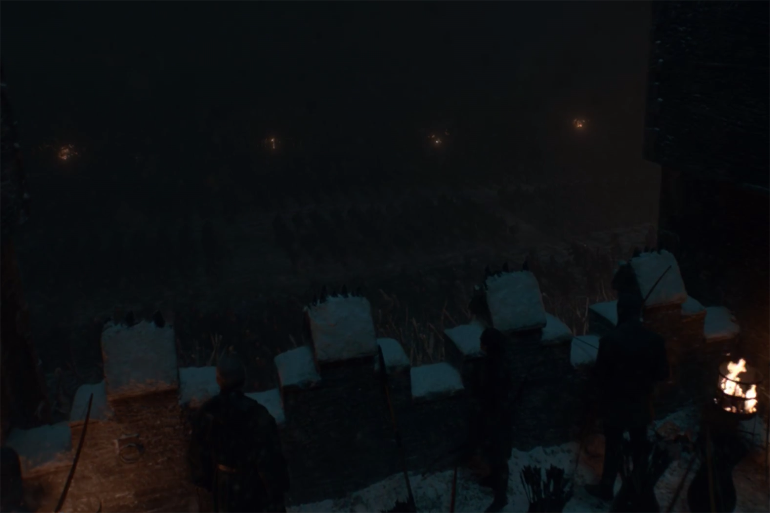 A still from Game of Thrones, showing a dimly-lit walkway over an extremely-dimly-lit battlefield.