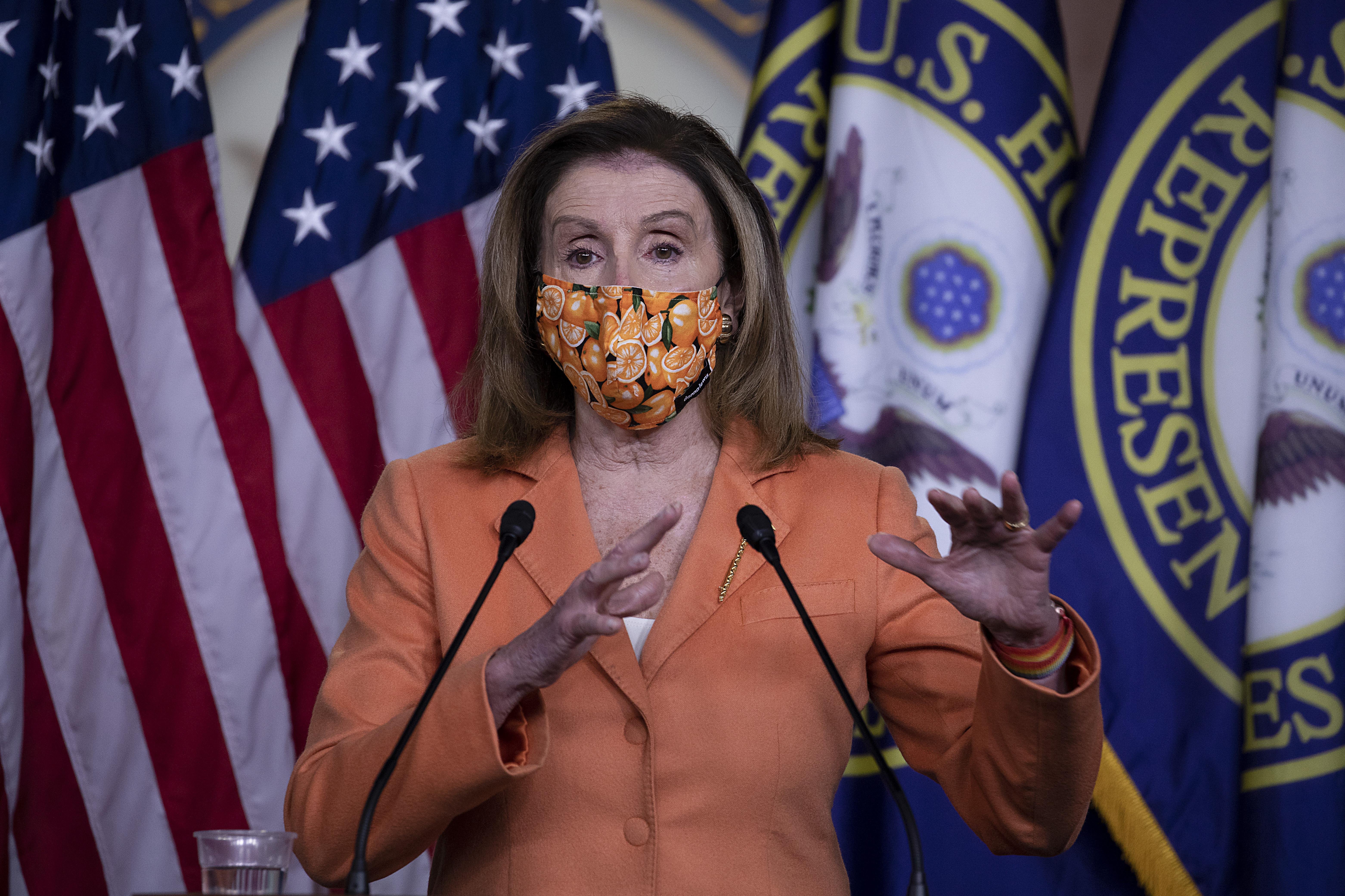 Nancy Pelosi, wearing a mask and gesturing with her hands, speaks at a press conference on Capitol Hill on Thursday