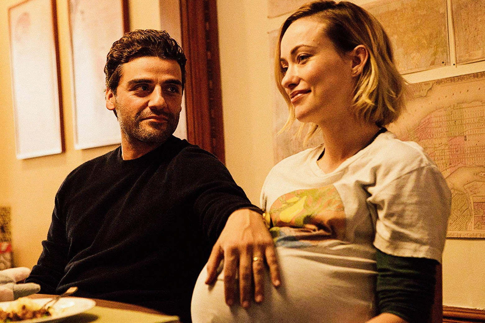 Oscar Isaac’s character rests his arm on the pregnant belly of Olivia Wilde’s character.