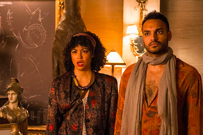 Riann Steele and Arjun Gupta stand together next to a bust.