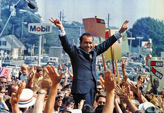 Richard Nixon gives his trademark "victory" sign.