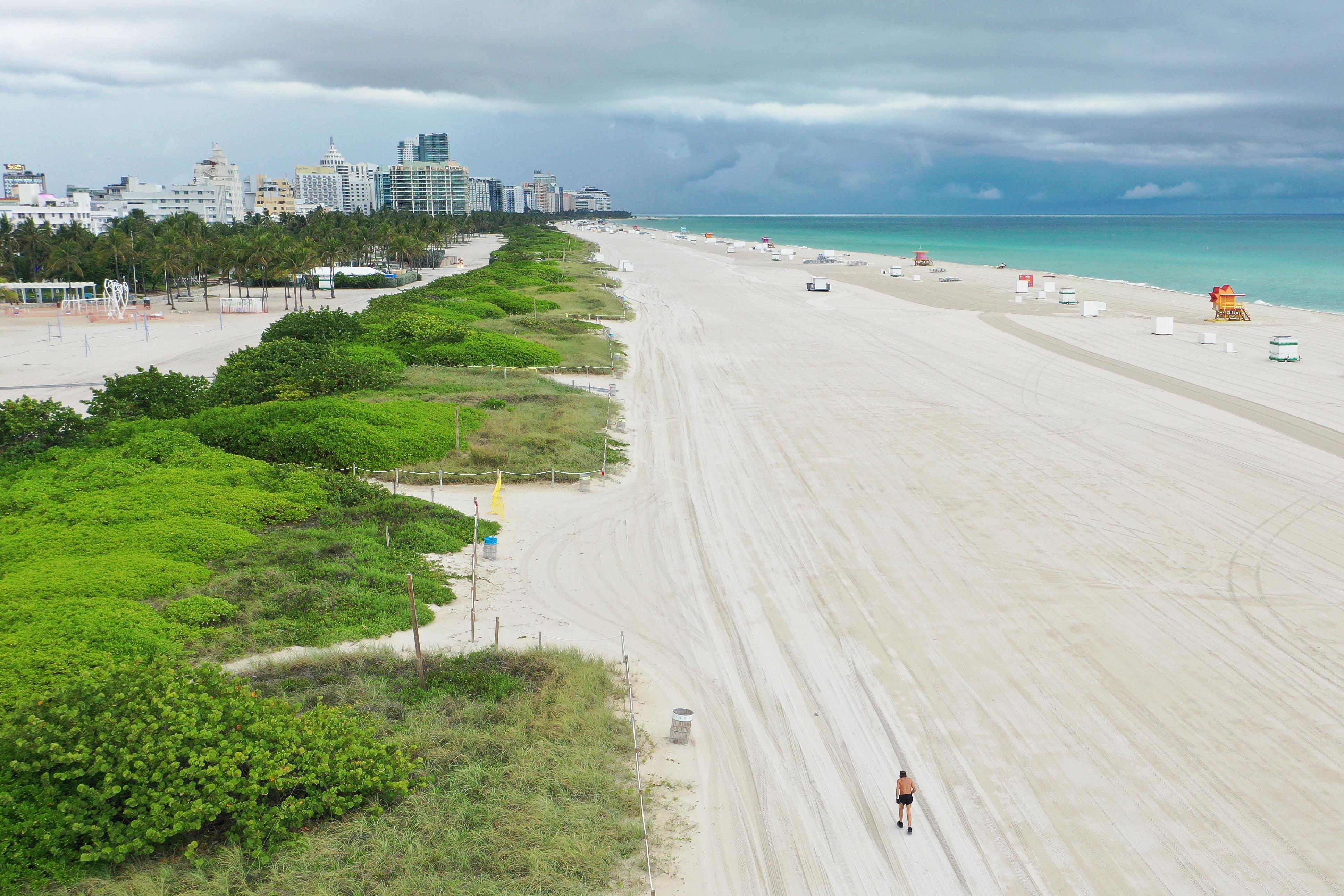 An aerial view of an empty beach, with the Miami skyline in the background.