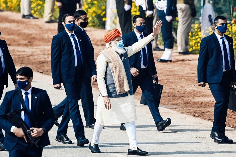 Narendra Modi waves as he walks amid a group of staff members and security.