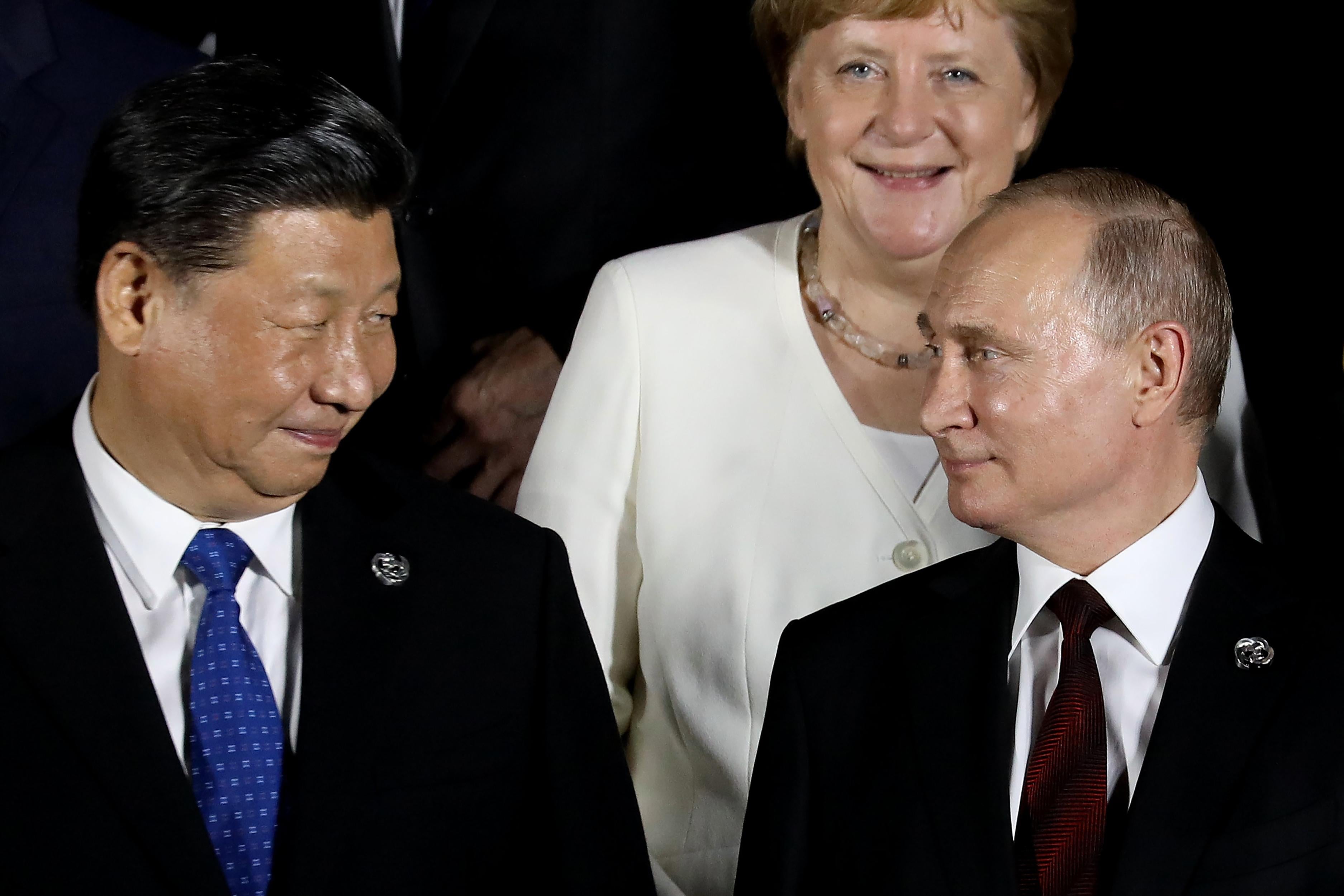 German Chancellor Angela Merkel stands behind Russian President Vladimir Putin and Chinese President Xi Jinping.