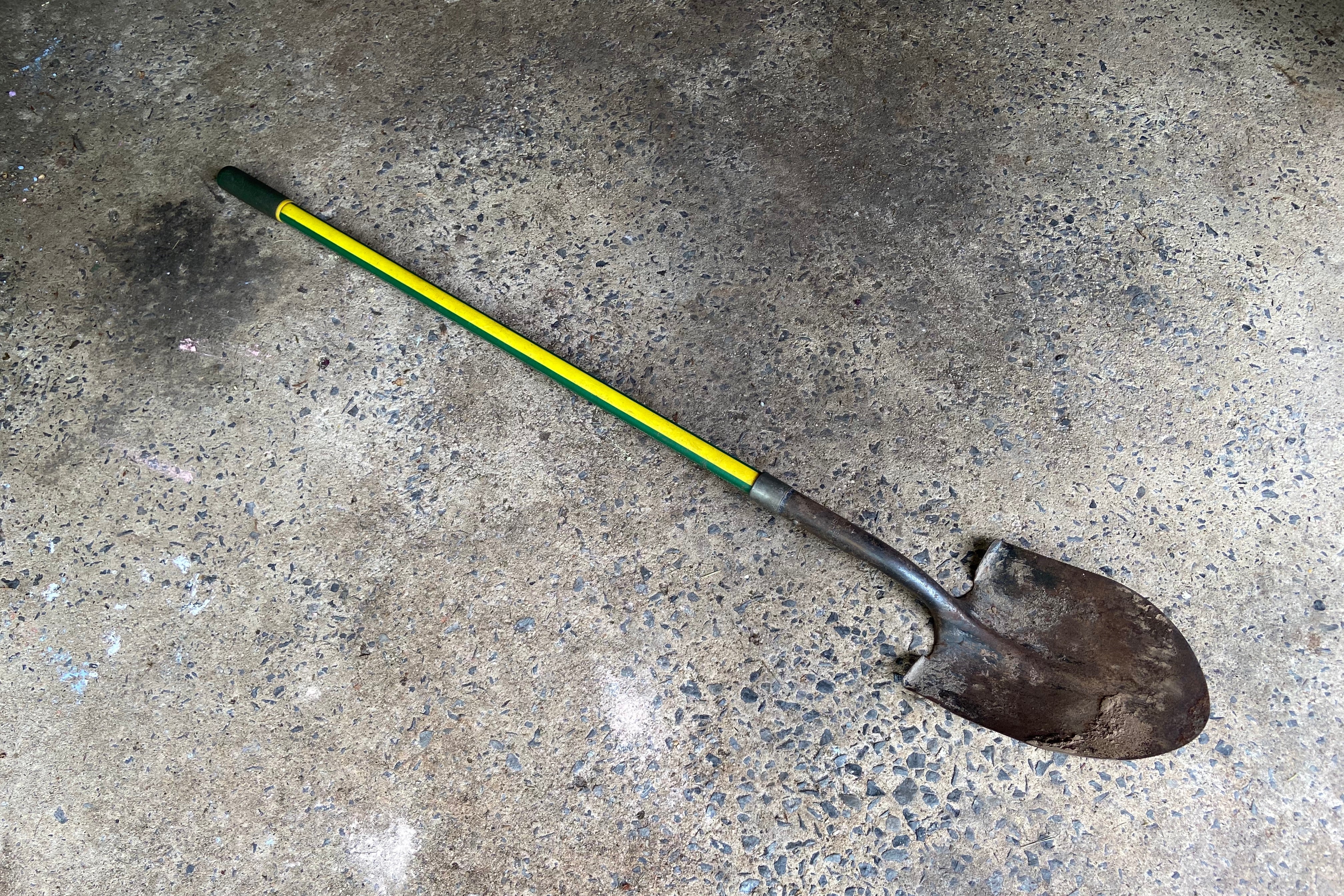 A garden shovel lying diagonally on concrete