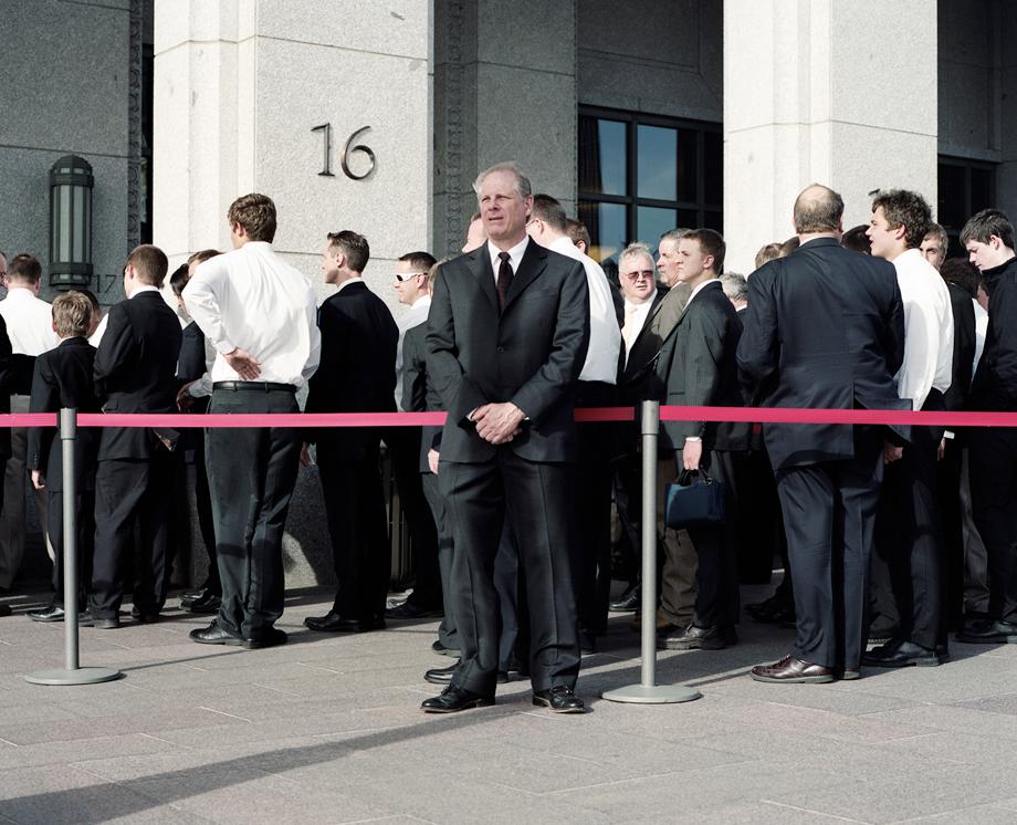 A Security Guard stands watch as men line up for the priesthood session at the LDS Conference Center during LDS General Conference in April 2012. Twice a year, the Mormon Church holds a "General Conference" where over 100,000 Mormons descend on Salt Lake City to hear teaching from leaders in the church and also to learn doctrine from their church president who they believe is a living prophet.
