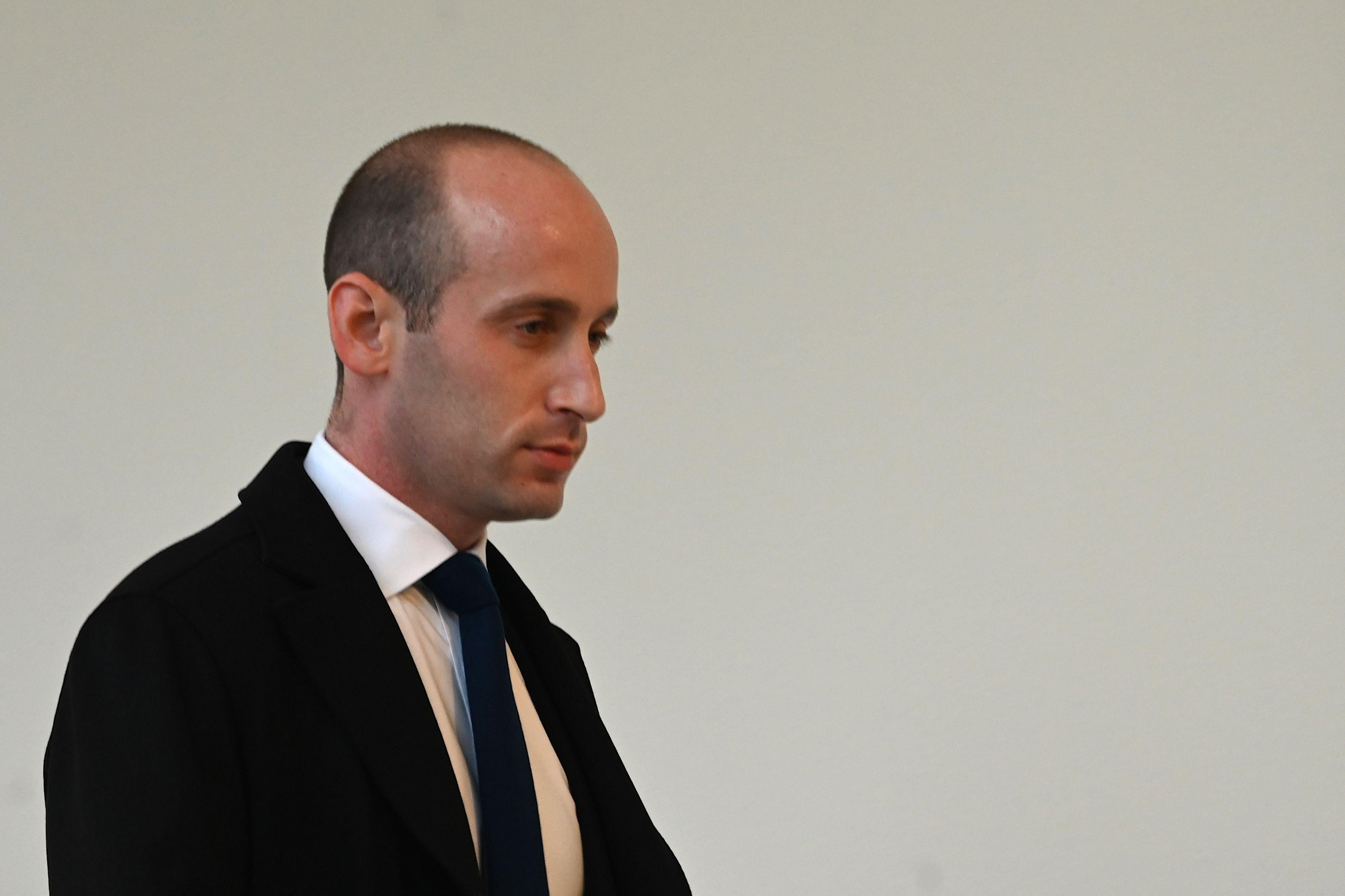 Stephen Miller, seen against a white wall and in a suit.