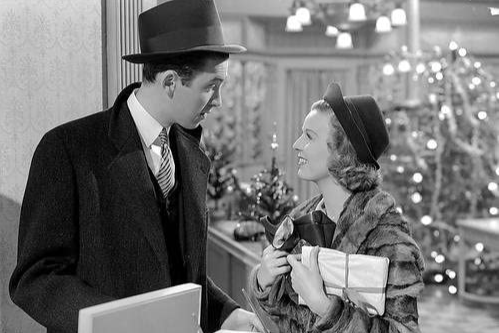 James Stewart wearing a trench coat and a top hat talks to Margaret Sullvan, who is wearing a fur coat and a hat.