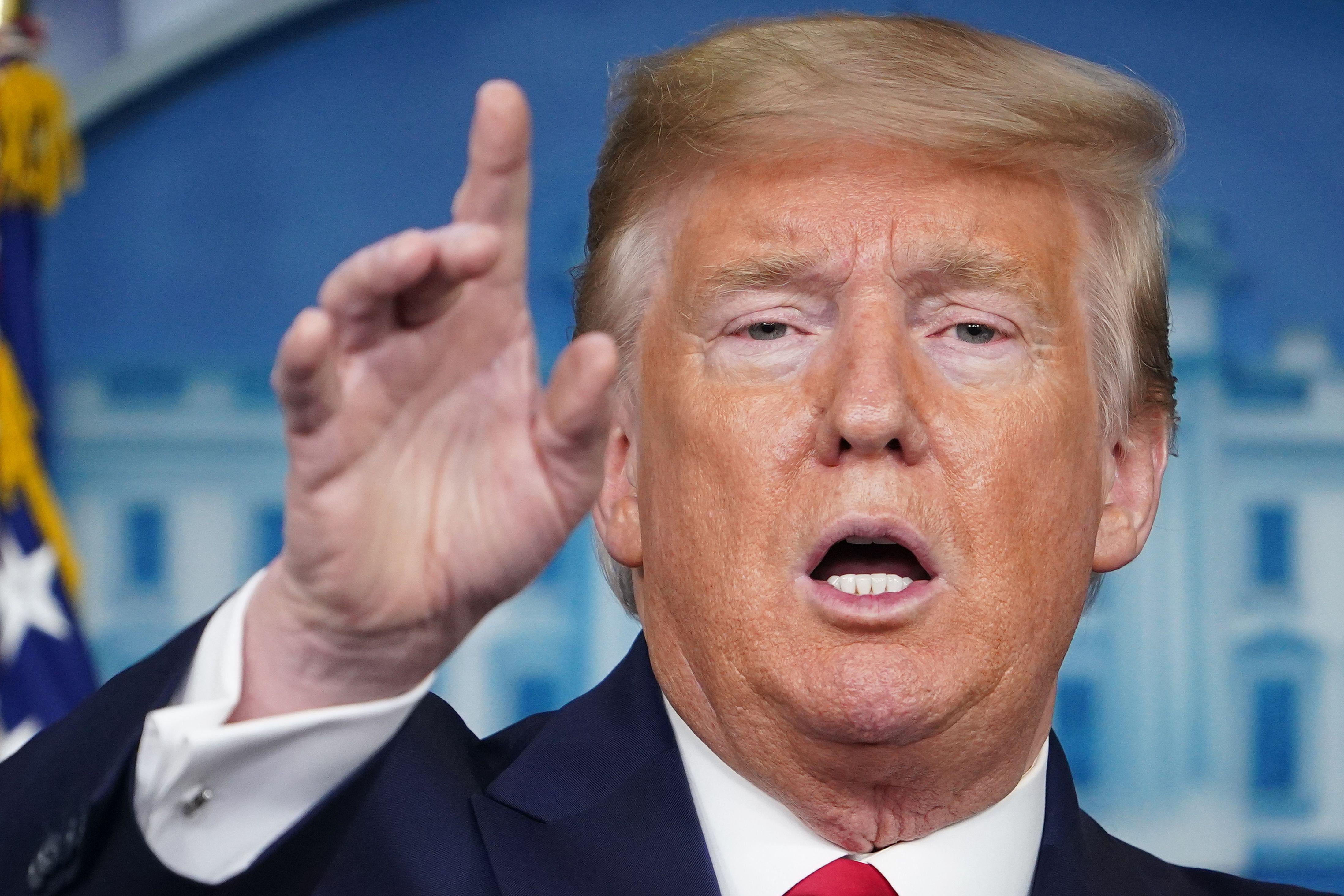 Donald Trump, mouth open, raising his hand 
